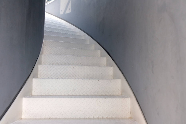 Escalier en colimaçon dans le bâtiment. Escaliers en métal blanc menant au couloir et aux murs gris
. - Photo, image
