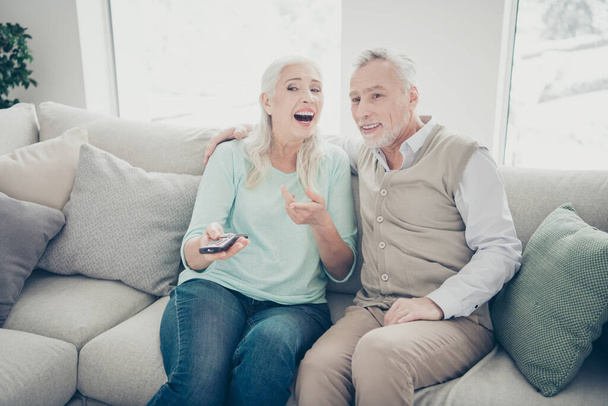 Photo of two aged people pair spending free time together watching humorous serial sitting cozy sofa - Zdjęcie, obraz