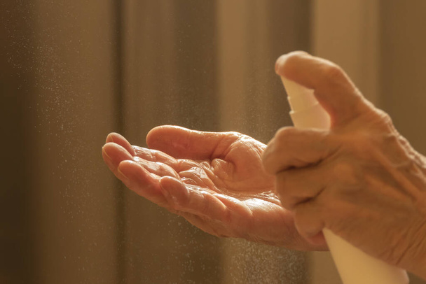 Starší běloška, která nanáší alkoholový sprej na čištění rukou, pomáhá chránit před koronavirem covid-19 - Fotografie, Obrázek