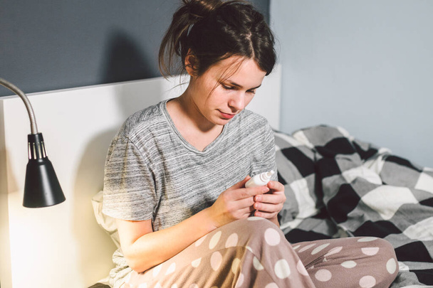 The theme is seasonal cold, runny nose flu virus infection. Young caucasian woman at home bedroom bed uses spray drops of medicine in her nose for snot. Allergic renitis and sinusitis. - Fotoğraf, Görsel