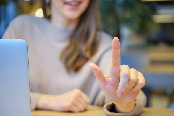 Mädchen mit Laptop am Tisch drückt abstrakt einen Finger. Nahaufnahme. - Foto, Bild