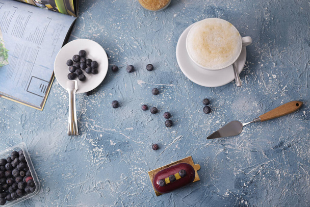 Incredibly beautiful red burgundy dessert with blueberries. Blueberries on a plate. Coffee latte breakfast. Layout on a blue creative background. Gorgeous photo of breakfast, sweets. Training food photo. - Foto, Imagem