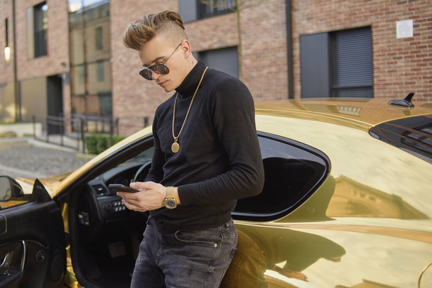 Successful freelancer, a man earns by phone, a man in a golden car, in gold chains. A rich man meets on the Internet. Man with glasses. - Фото, изображение