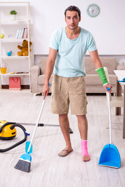 Fiatal sérült férfi takarítja a házat. - Fotó, kép