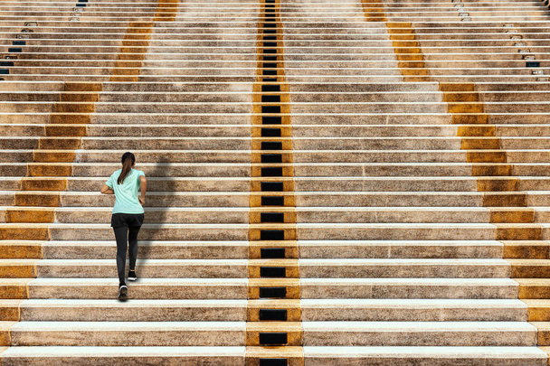Young woman running up in urban stairs concrete background. - Photo, Image