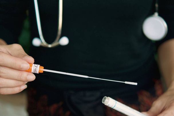 Una doctora sosteniendo un hisopo estéril en su mano, se preocupó por las situaciones de Covid-19.
. - Foto, Imagen