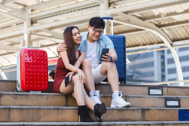 asiatique couple touriste avec bagage en utilisant smartphone recherche d'hébergement et d'attraction touristique
. - Photo, image