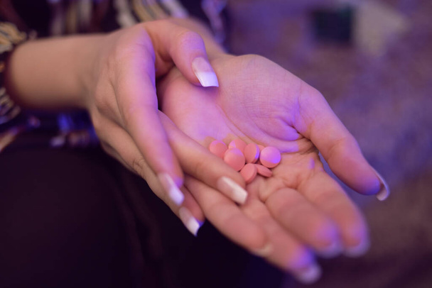Het meisje heeft pillen in haar handen. Vrouwelijke handen houden veel pillen vast. Handen vasthouden roze, witte pillen, medicijnen. Coronavirus tabletten. - Foto, afbeelding