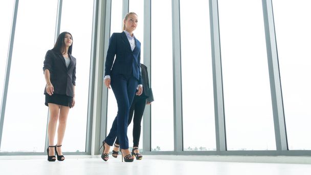 Full length of group of confidence young business woman people colleague teamwork walking the corridor in office together. - 写真・画像
