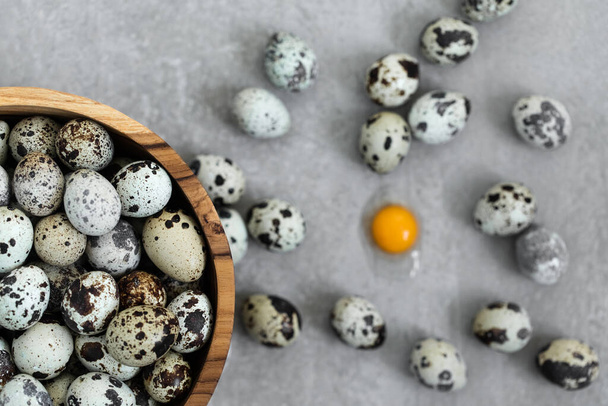 Wooden bowl with heap of small quail eggs on gray concrete background. Easter cooking concept. - Photo, Image