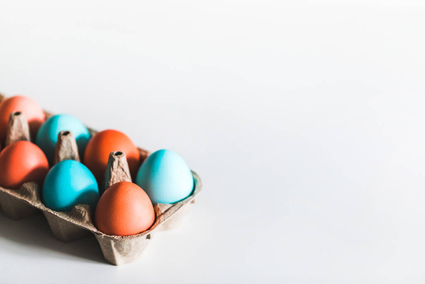 Βαμμένα πασχαλινά αυγά σε χαρτόκουτο σε λευκό φόντο. Μοντέρνο μπλε και κόκκινο χρώμα. Στο πάνω μέρος. Έννοια Paschal. - Φωτογραφία, εικόνα