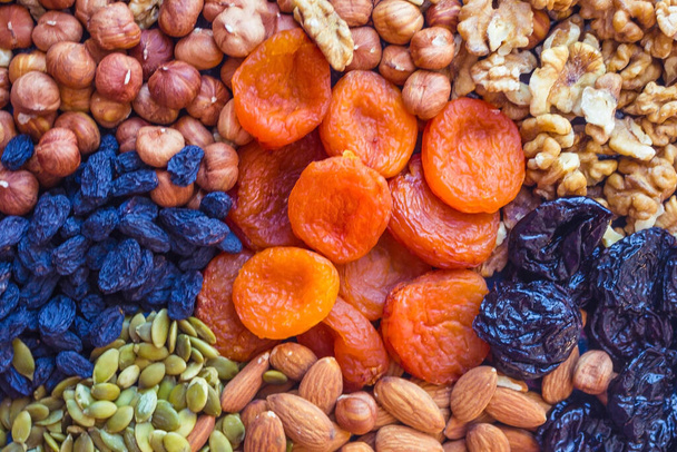 Dried fruits and peeled nuts in stock. Abundance, delicious and healthy food. Vegetarian menu. Warm tones, top view. - Photo, Image