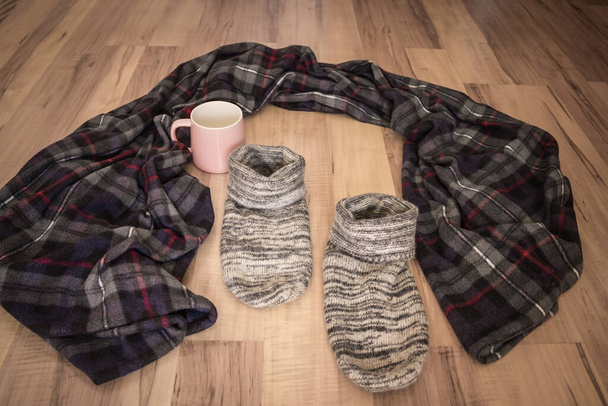 Leave the familiar surroundings, home environment, comfort zone. Left blanket, mug and socks on the wooden floor. Vignetting. - Photo, Image