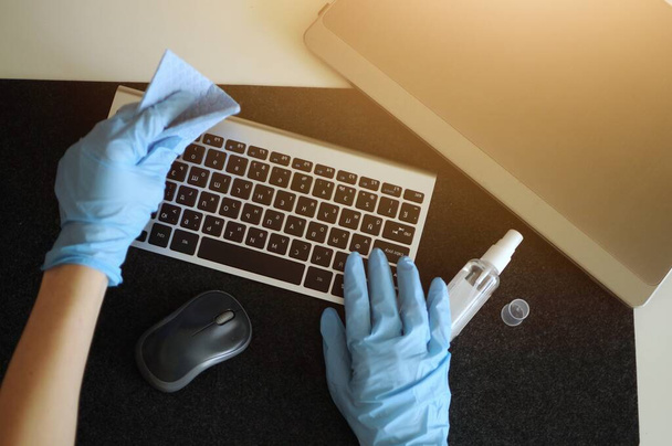 Mujer prevenir enfermedades mediante la desinfección del dispositivo de teclado en el lugar de trabajo
 - Foto, imagen