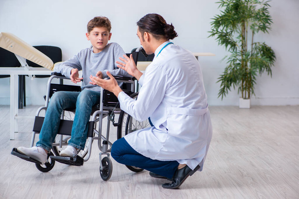 Young male doctor pediatrist and boy in wheel-chair - Φωτογραφία, εικόνα