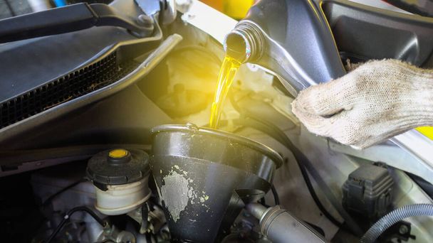 Frisches Öl wird während eines Ölwechsels in ein Auto gegossen - Foto, Bild