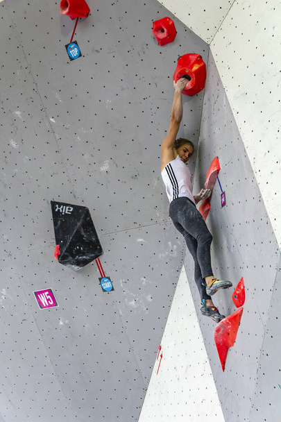 Zakopane, Poland - September 06, 2019: A young Slovenian representative in bouldering is holding a grip in a climbing problem (boulder) arranged by the route setter on the climbing wall. - Фото, изображение
