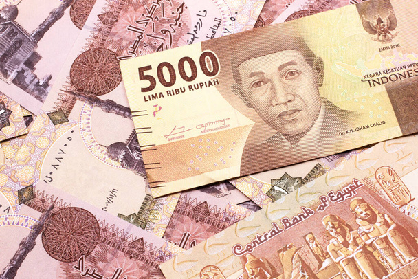 Pomarańczowy, pięć tysięcy rupii indonezyjski banknot bankowy z egipskimi banknotami funtowymi zamkniętymi w makro - Zdjęcie, obraz
