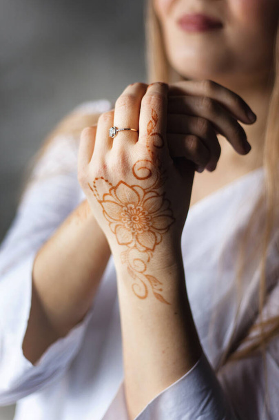 Girl of European appearance, henna drawing on hands, mahendi, girl in light clothes, yoga, spiritual development - Foto, afbeelding