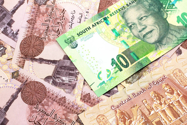Egy közeli kép egy zöld 10 rand bankjegyről Dél-Afrikából makróban egy egyiptomi egyfontos bankjegy ágyán. - Fotó, kép