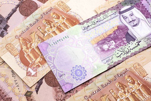Une image rapprochée d'un billet de cinq rials d'Arabie Saoudite sur fond de billets de banque égyptiens d'une livre en macro
 - Photo, image