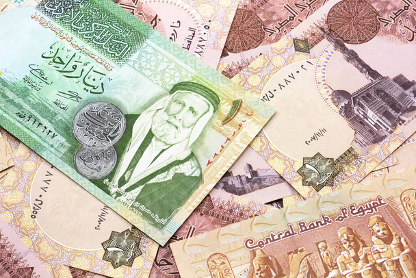 Makroaufnahme einer Ein-Dinar-Banknote aus Jordanien auf einem Bett ägyptischer Ein-Pfund-Banknoten in Nahaufnahme - Foto, Bild
