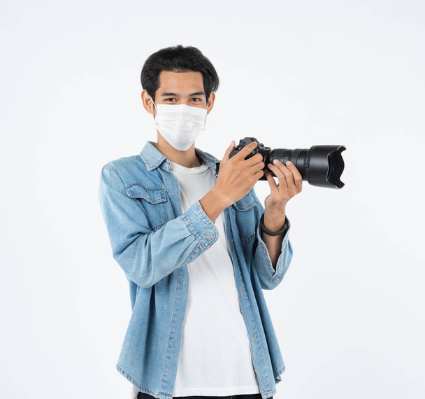 Védelem a fertőző betegség, koronavírus.Ázsiai fényképezőgép fotós fiatalember visel higiénikus maszk fertőzés megelőzésére, levegőben terjedő betegség, Covid-19 lövés stúdióban elszigetelt fehér alapon. - Fotó, kép