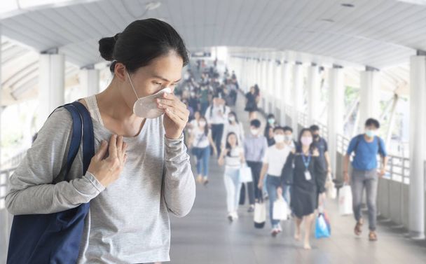 Азійська жінка носить хірургічну маску обличчя, кашель і біль у грудях з розфокусованою маскою для захисту від вірусу і ходьби по дорозі, розмите тло, коронавірус, коїд-19 пандемічна концепція - Фото, зображення