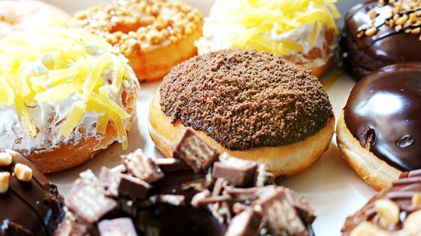 Großaufnahme Gruppe glasierter Donuts auf Tablett, schmackhafter, mehrfach sortierter Donut, selektiver Donut mit Fokus auf Donut. - Foto, Bild