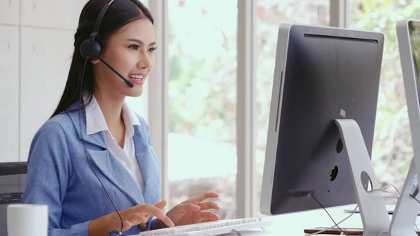 Customer support agent or call center with headset works on desktop computer while supporting the customer on phone call. Operator service business representative concept. - Photo, Image