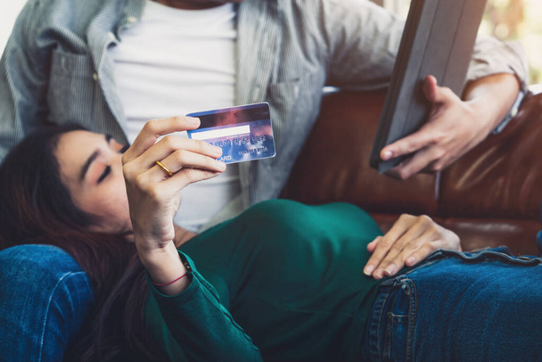Junges Paar nutzt Kreditkarte für Online-Einkäufe auf Internet-Website zu Hause. Die Nummer auf der Kreditkarte ist eine Attrappe. Keine persönlichen Daten auf der Kreditkarte. Online-Shopping-Konzept. - Foto, Bild