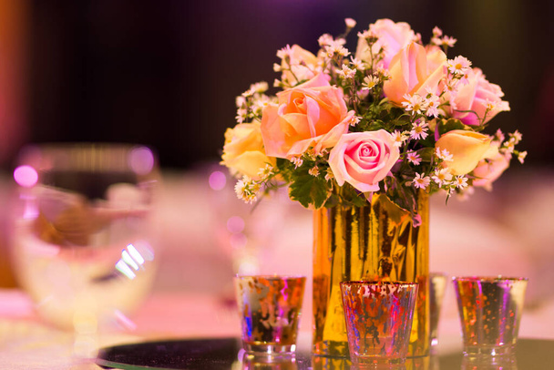 róża kwiaciarnia w dekoracji szklanego wazonu na stole obiadowym ze srebrem i świecą Indyjski ślub ustawienie kryty z dekoracyjnymi światłami i pięknym bokeh. - Zdjęcie, obraz