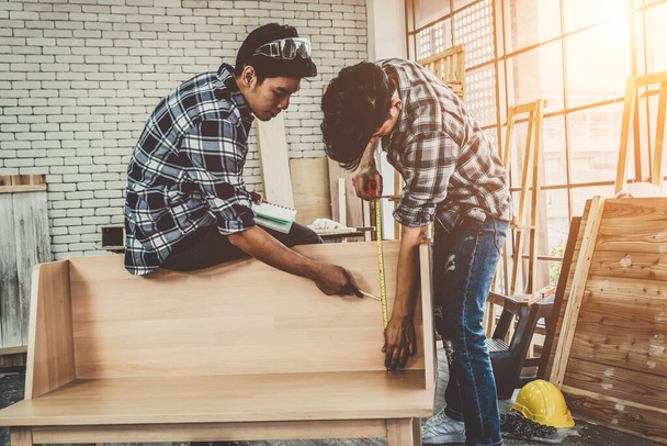 Tischler, der in einer Werkstatt mit Holzhandwerk beschäftigt ist, um Baumaterial oder Holzmöbel herzustellen. Der junge asiatische Tischler setzt professionelle Werkzeuge zum Basteln ein. Heimwerker und Zimmerer arbeiten Konzept. - Foto, Bild