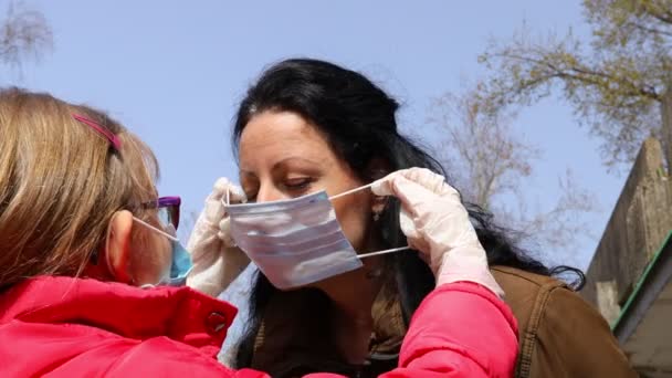 Little girl is putting medical mask on her mother face.Daughter is putting medical mask on her mother face for protection against virus COVID-19, Corona. Canon EOS R 4K ALL-I - Felvétel, videó