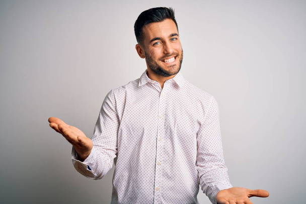 Young handsome man wearing elegant shirt standing over isolated white background smiling cheerful with open arms as friendly welcome, positive and confident greetings - Φωτογραφία, εικόνα
