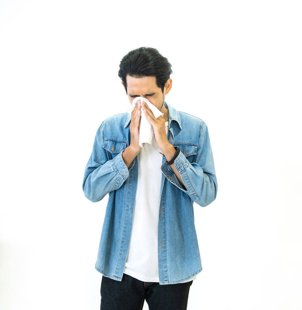 Junger asiatischer gutaussehender Mann in lässigem Jeanskleid mit Grippesaison und Niesen mit Papiertaschentüchern verhindert die Ausbreitung von Viren und Bakterien isoliert auf weißem Hintergrund, Gesundheits- und Krankheitskonzepte - Foto, Bild