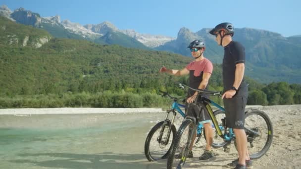 SLOW MOTION: Friends riding bikes along Soca river talk while observing nature - Footage, Video