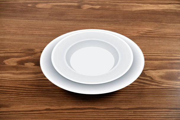 Пустая тарелка на деревянном фоне стола
 - Фото, изображение