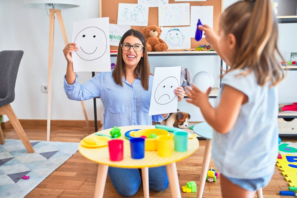 Young therapist woman speaking and treating child, counselor and behaviour correction at pedagogue payroom showing happy and sad faces - Fotoğraf, Görsel