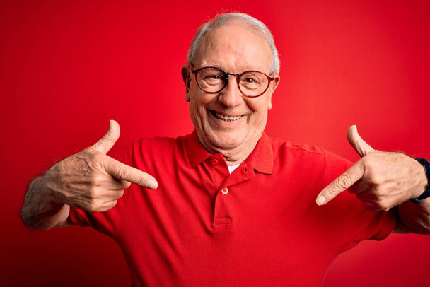 Grey haired senior man wearing glasses and casual t-shirt over red background looking confident with smile on face, pointing oneself with fingers proud and happy. - Φωτογραφία, εικόνα