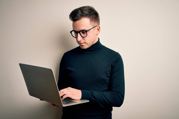 Молодой красивый кавказский бизнесмен в очках с помощью ноутбука с уверенным выражением на умном лице думает серьезно
 - Фото, изображение