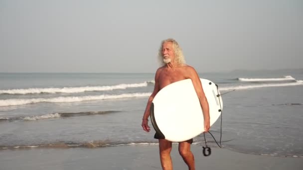 Avô com uma prancha na praia. Velho maduro surfista masculino
 - Filmagem, Vídeo