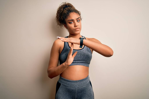 Young african american sportswoman doing sport wearing sportswear over white background Doing time out gesture with hands, frustrated and serious face - Photo, Image