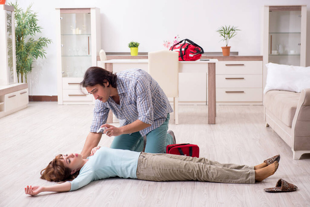 Young couple in first aid concept at home - Фото, зображення