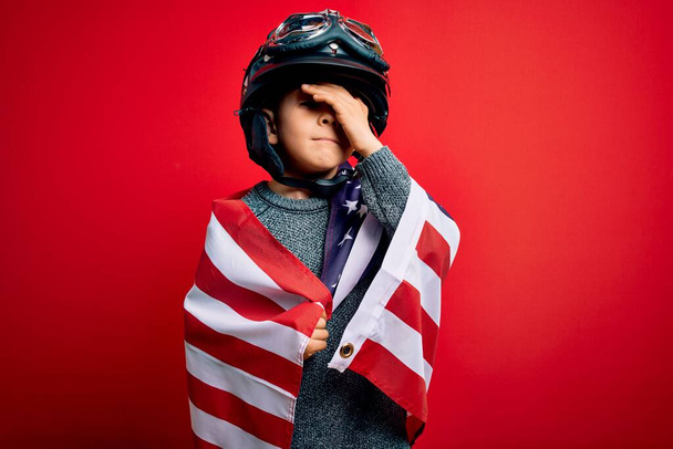 Νεαρό μικρό πατριωτικό παιδί φορώντας σημαία των Ηνωμένων Πολιτειών Αμερικής και κράνος μοτοσικλέτας στις 4 Ιουλίου τόνισε με το χέρι στο κεφάλι, συγκλονισμένος από ντροπή και έκπληξη πρόσωπο, θυμωμένος και απογοητευμένος. Φόβος και αναστάτωση για λάθος. - Φωτογραφία, εικόνα