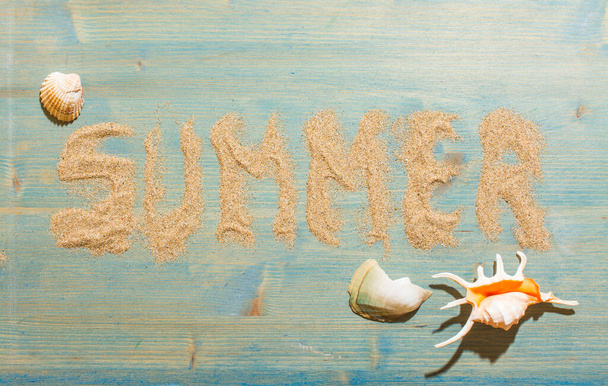 Kum ve deniz kabukları mavi ahşap üzerinde "Summer" kelimesiyle. Kopya alanı olan bir arkaplan. Üst görünüm - Fotoğraf, Görsel