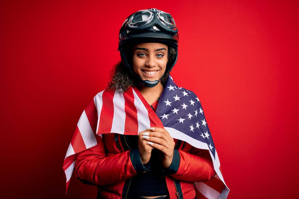Afro-Amerikaanse patriottische motorrijder meisje dragen moto helm dragen van de Verenigde Staten vlag met een gelukkig gezicht staan en glimlachen met een zelfverzekerde glimlach tonen tanden - Foto, afbeelding