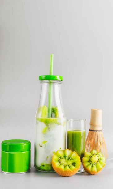 Healthy vegan layered matcha latte drink in bottle with drinking straw standing on table at light gray background. Matcha espresso. Clean eating, detox beverage, dairy food concept. Summer drinks - Foto, Imagen