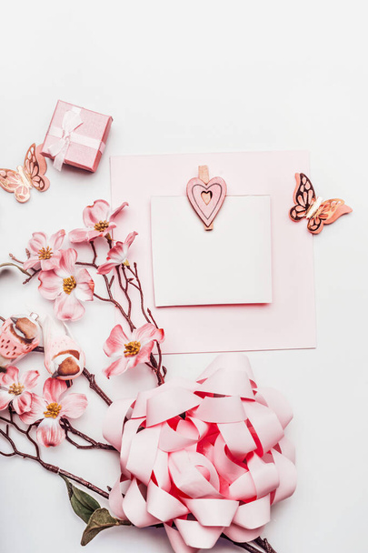 Stylish greeting card mock up with flowers, ribbon, little gift box and hearts in coral color on white background, top view. Wedding,Mothers day , birthday or abstract love concept. Flat lay. Blog - Фото, изображение