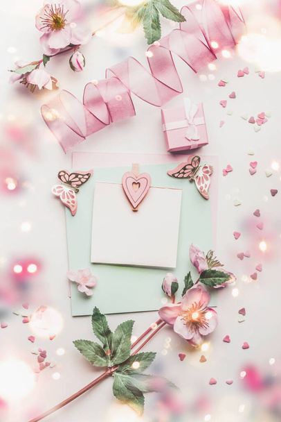 Lovely greeting card composition in pastel color with mock up, flowers and little gift box, hearts and handicraft decoration accessories, top view - Photo, Image